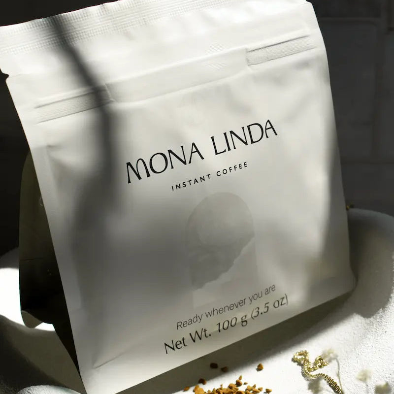 Mona Linda instant coffee pouch standing upright with coffee crystals around it.